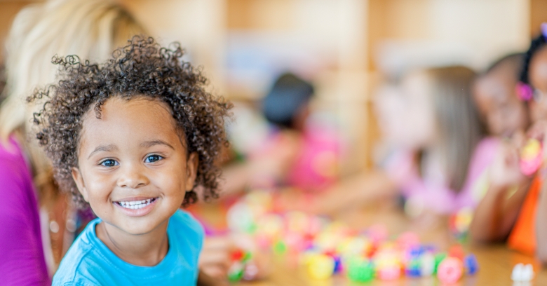 Child smiling at camera with blurred kids in background