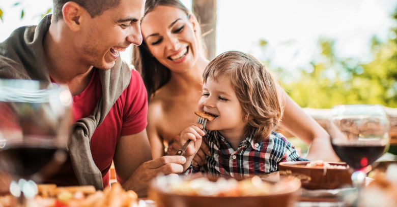 A mother, father, and child eating at a table