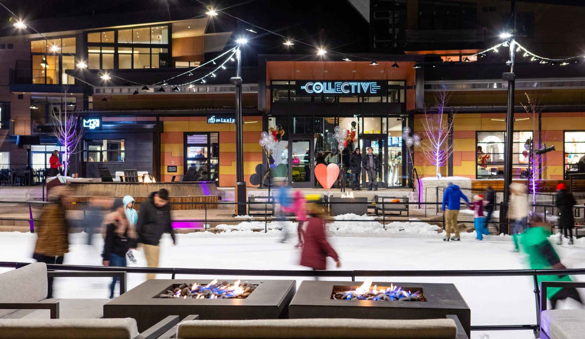 People ice skating in an outdoor rink at night