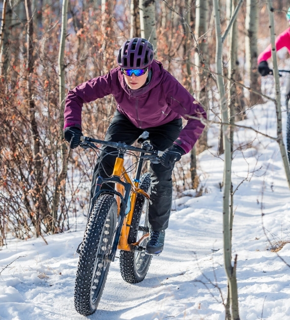 People mountain biking through snowy woods