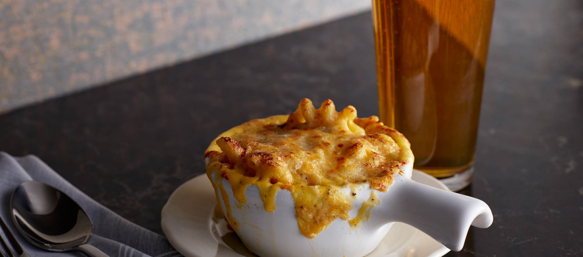 bowl of mac and cheese with pint of beer