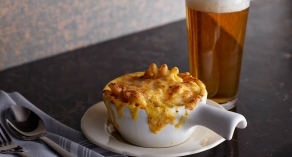 bowl of mac and cheese with pint of beer