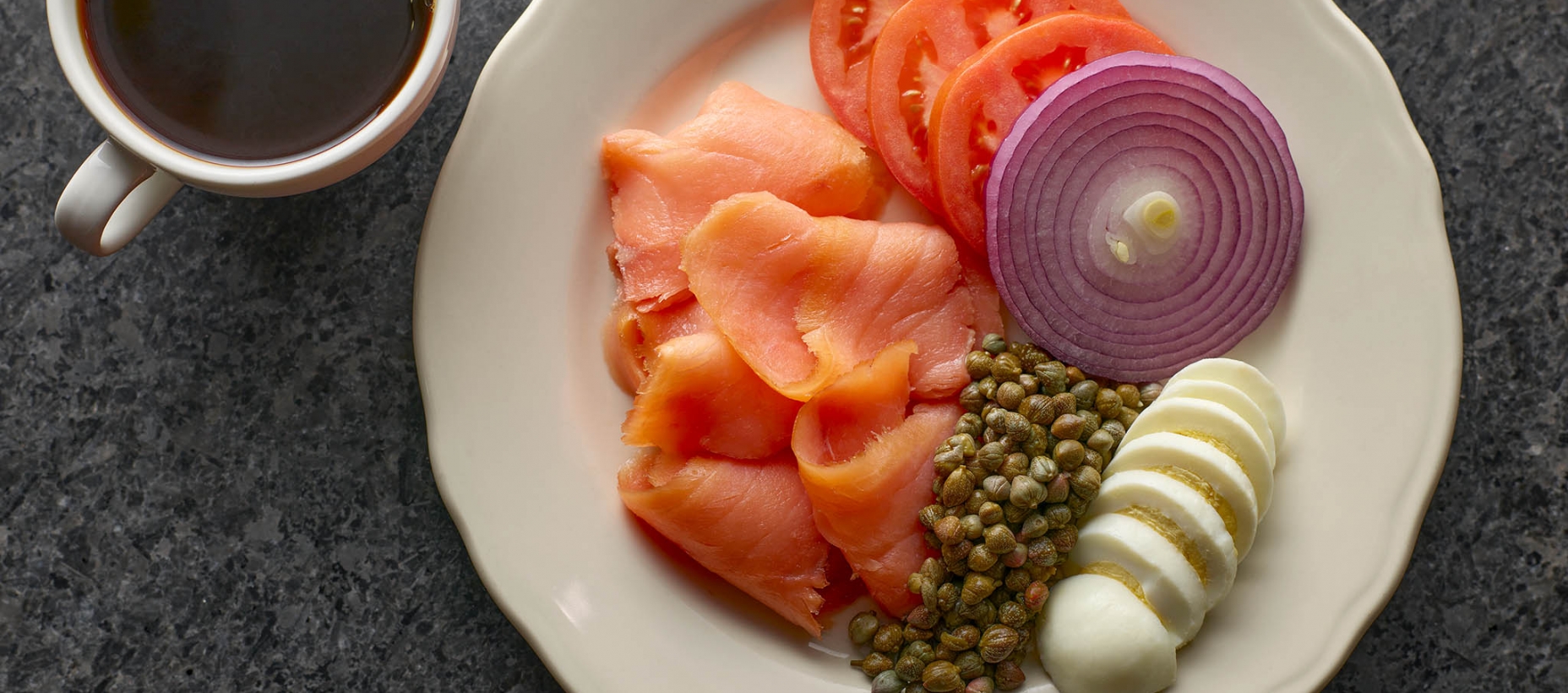 plate of smoked salmon. tomatoes, red onions, eggs, and capers