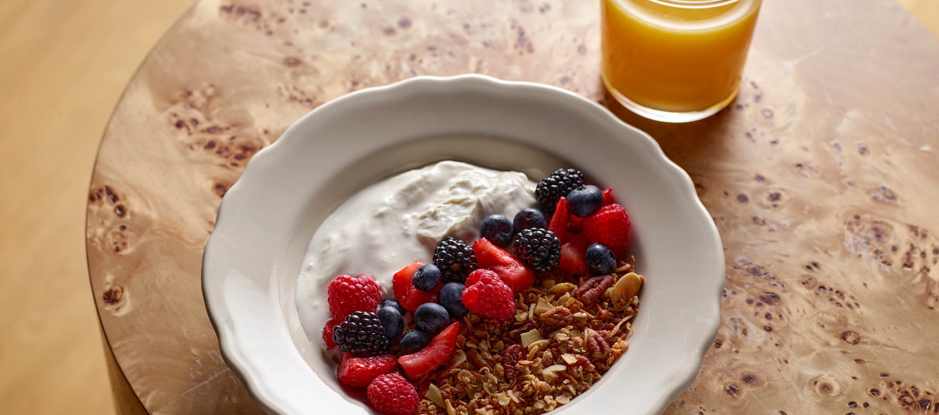 Bowl of Granola with fruits and yogurt and a cup of orange juice