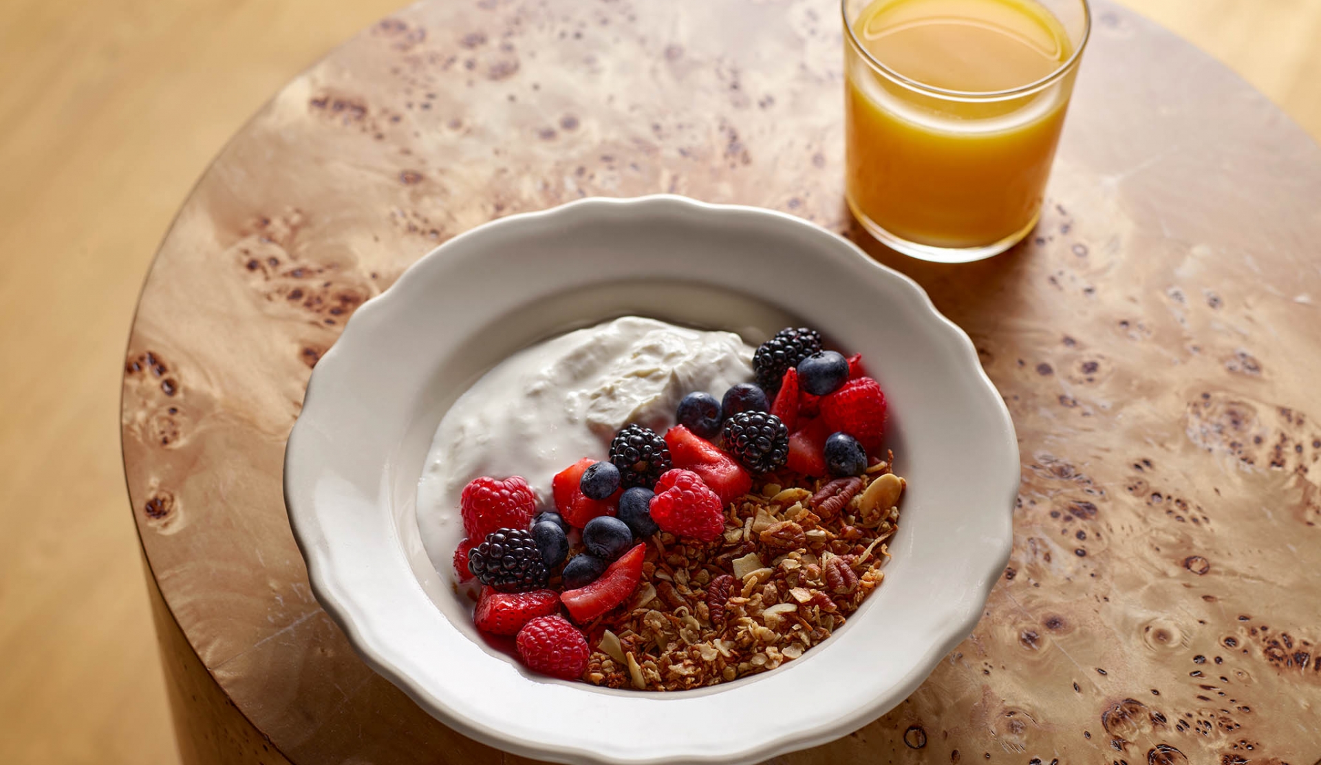 Bowl of Granola with fruits and yogurt and a cup of orange juice