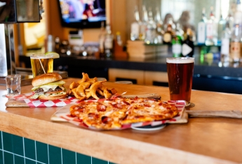Pizza and beer sitting on a bar counter
