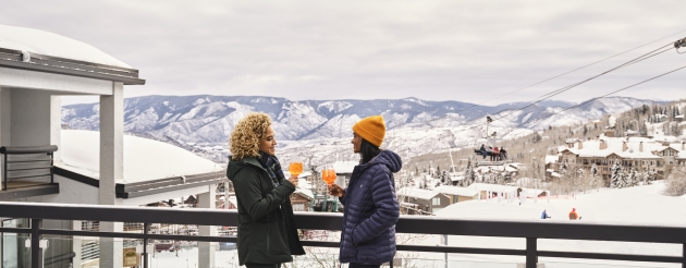 two women on snowy balcony overlooking mountains