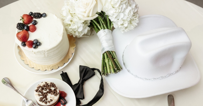 wedding cake with a bouquet and western hat on table for wedding
