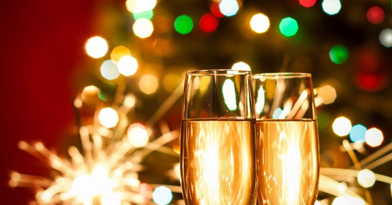 festive tree in background with sparkles and glasses of champagne in foreground